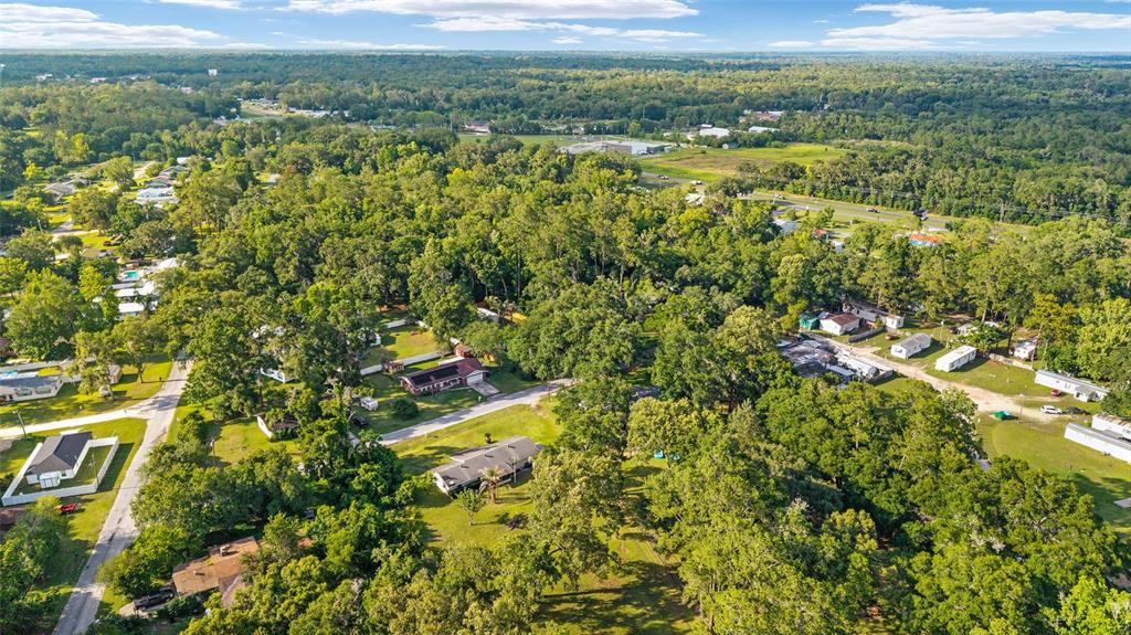 An aerial view shows a residential neighborhood surrounded by dense trees and green space — 2550 SE 67TH STREET, OCALA, FL