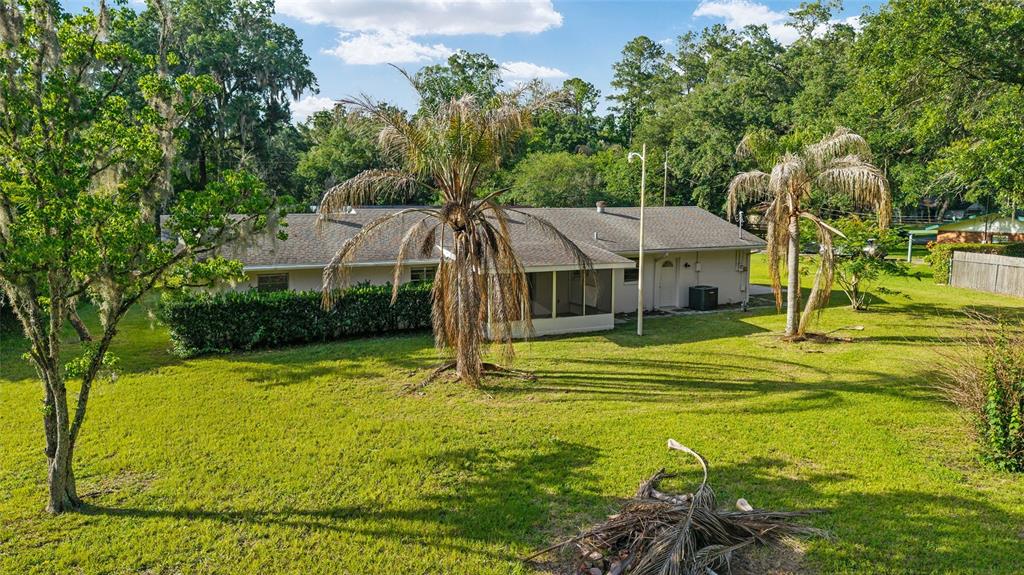 A single-story house with a screened porch sits on a large, grassy lot with palm trees — 2550 SE 67TH STREET, OCALA, FL