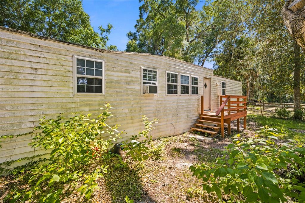 An exterior view of a weathered mobile home with a wooden deck and stairs — 14000 NE 47TH AVENUE, ANTHONY, FL
