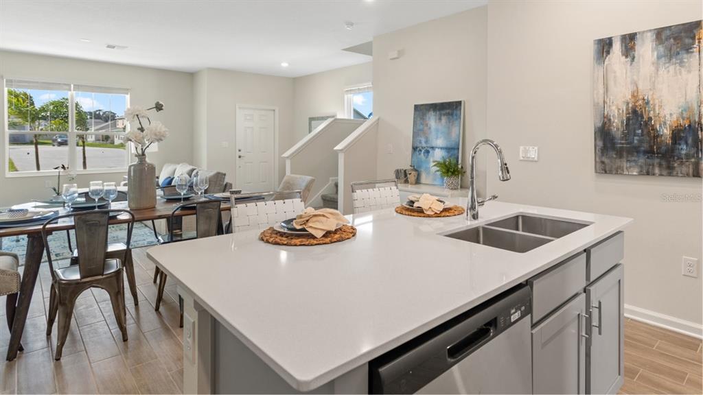 A kitchen island with a stainless steel sink sits before a dining area and stairs — 5658 KETTLEBELL ALLEY, CLERMONT, FL