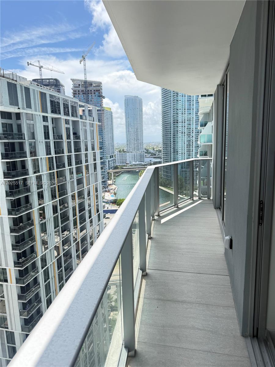 A balcony with glass railings overlooks a city canal and surrounding high-rise buildings — 77 SE 5 # 2307, Miami FL 33131, MIAMI, FL