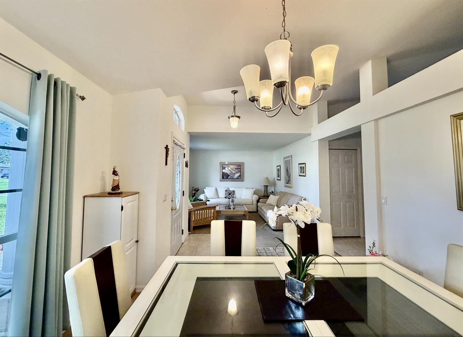 An open-concept kitchen with wood cabinets, white appliances, and tile flooring overlooks a living area — 2906 Serenity Circle S, Fort Pierce FL 34981, FORT PIERCE, FL
