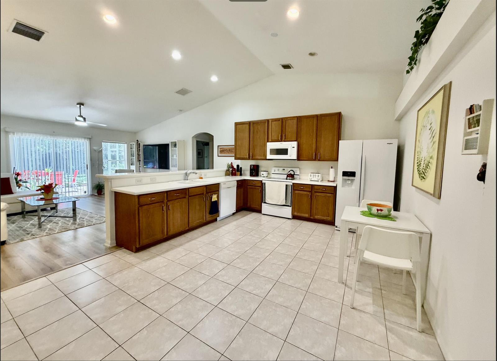A living room with white sectional seating, bar stools, and light wood-look flooring — 2906 Serenity Circle S, Fort Pierce FL 34981, FORT PIERCE, FL