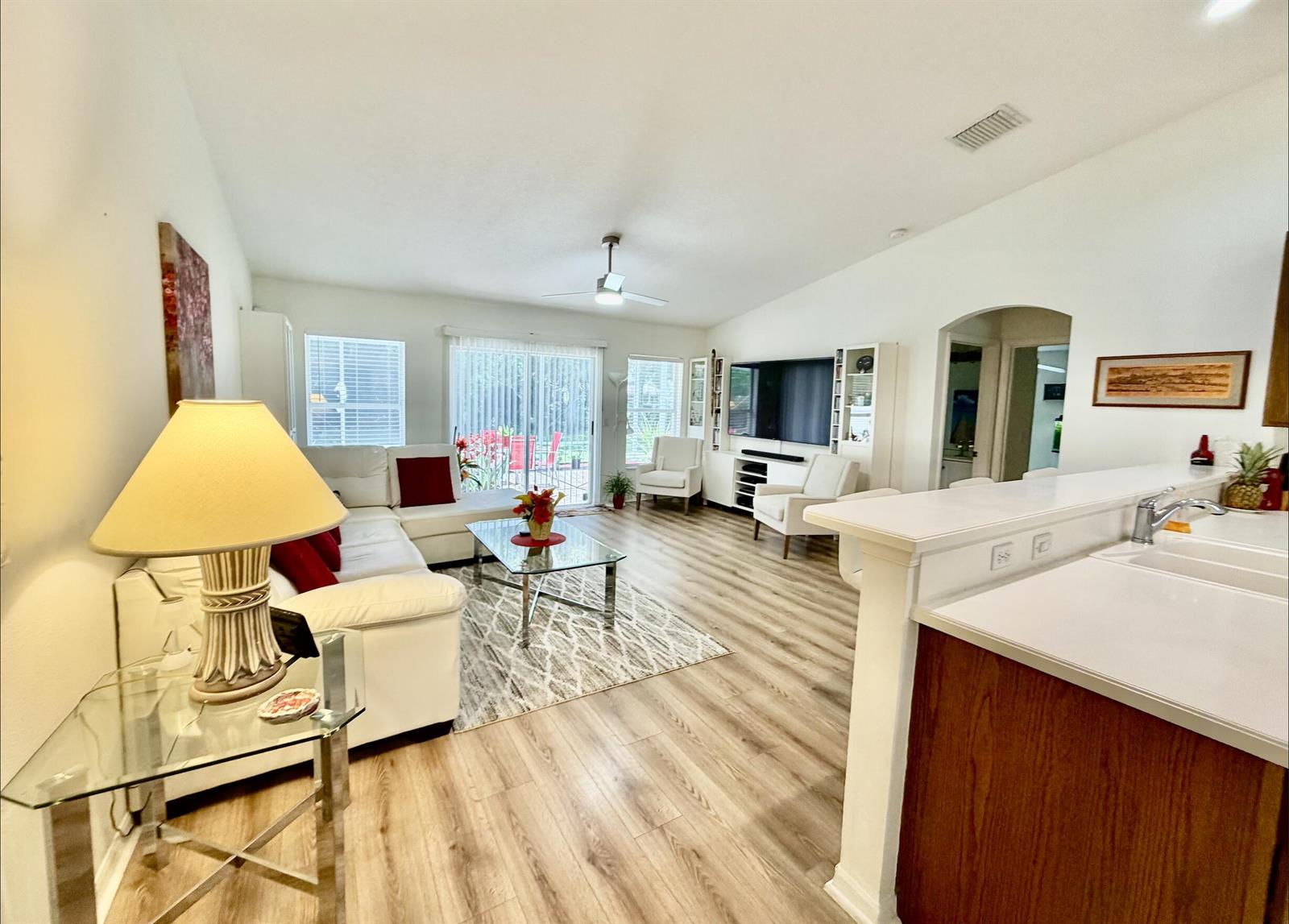 A living room features a white sectional sofa, light wood flooring, and a ceiling fan — 2906 Serenity Circle S, Fort Pierce FL 34981, FORT PIERCE, FL