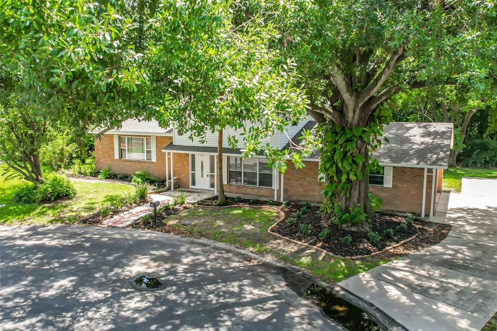 A two-story brick house with a large tree in the front yard and driveway — 1631 MONTEREY LANE, LAKELAND, FL
