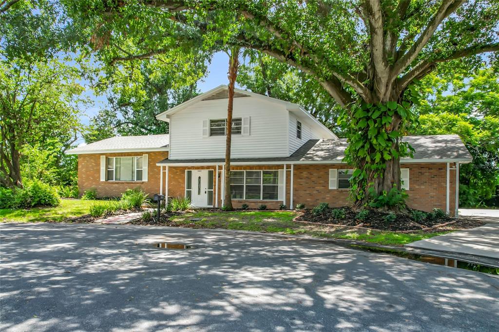 A two-story house with a brick and white siding exterior sits behind a large tree — 1631 MONTEREY LANE, LAKELAND, FL