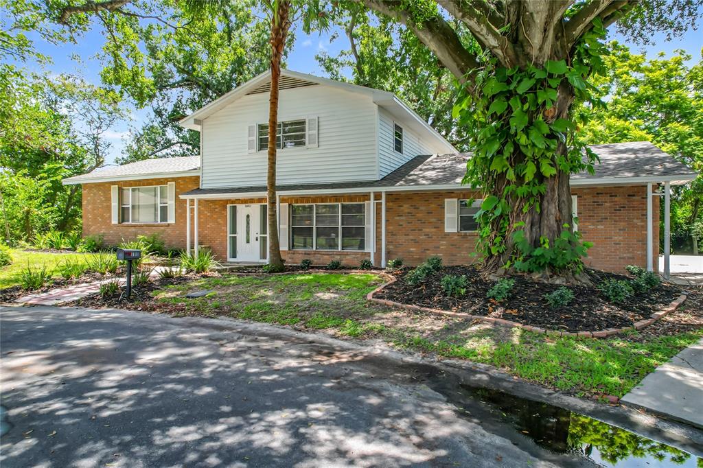 A two-story brick and white siding house with a large tree in the front yard — 1631 MONTEREY LANE, LAKELAND, FL