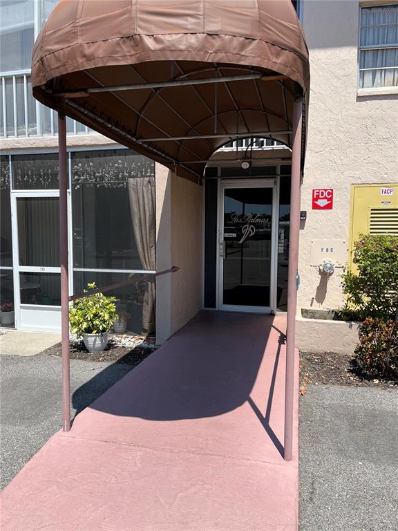 A brown fabric awning covers the entrance to a building with a glass door — 519 ALBEE FARM ROAD UNIT 303, VENICE, FL