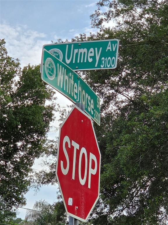 A stop sign is mounted below street signs for Urmey Avenue and Whitehorse Street — 3227 URMEY AVENUE, DELTONA, FL