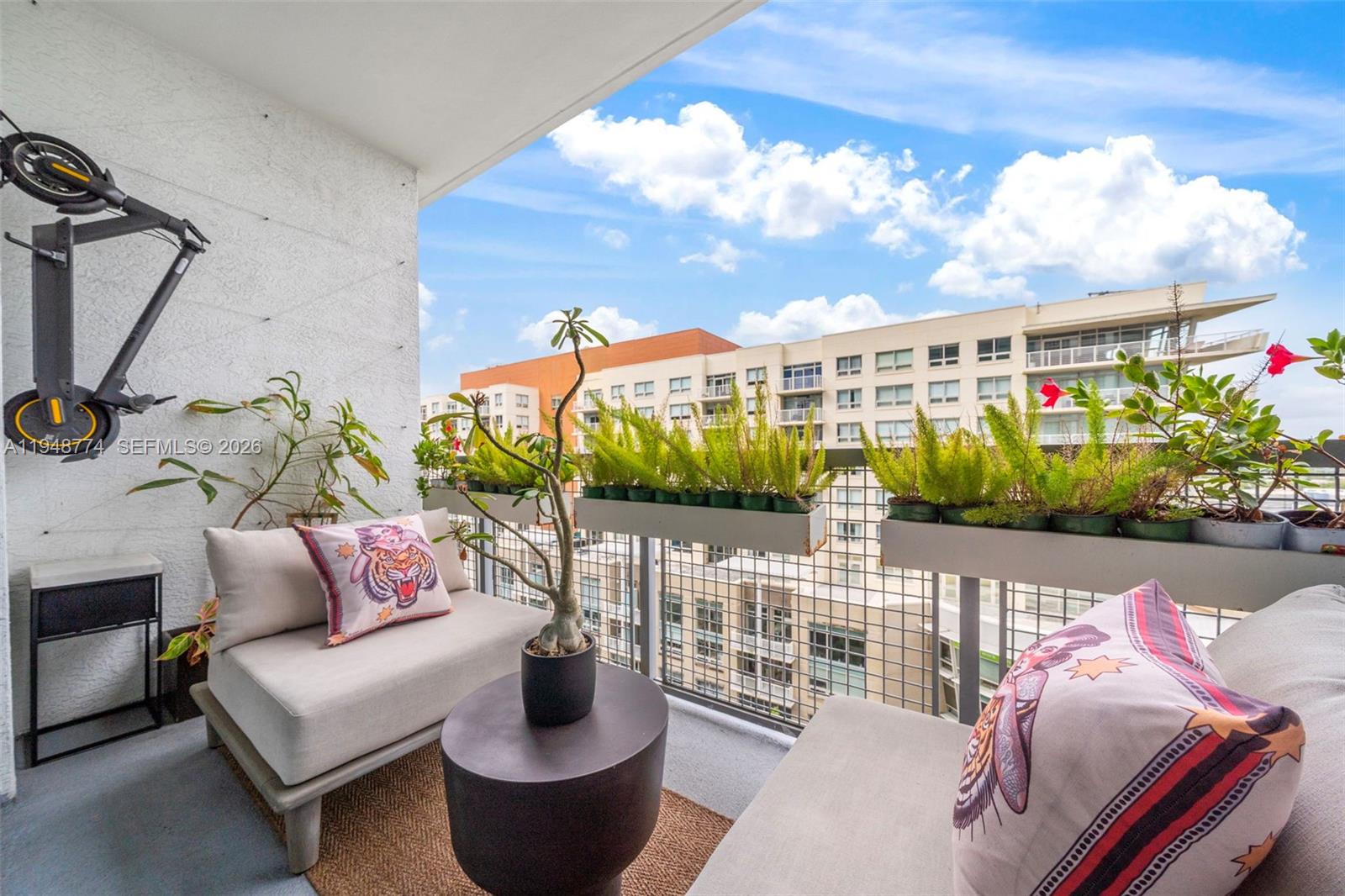 A balcony features two lounge chairs, a small table, potted plants, and a wall-mounted scooter — 3301 NE 1st Ave # H0805, Miami FL 33137, MIAMI, FL