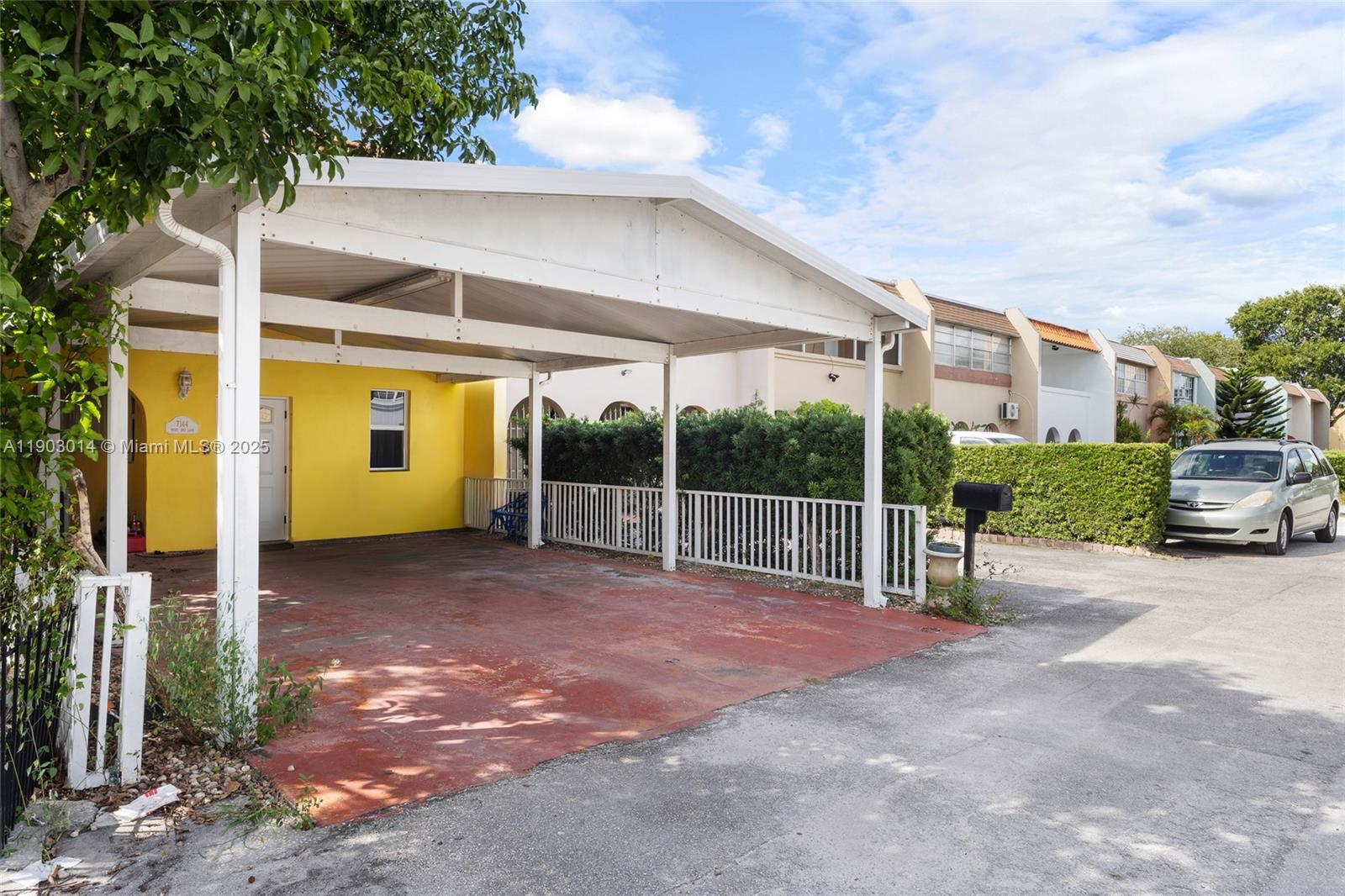 A yellow house features a large white carport and a paved driveway — 7144 W 2nd Ln, Hialeah FL 33014, HIALEAH, FL