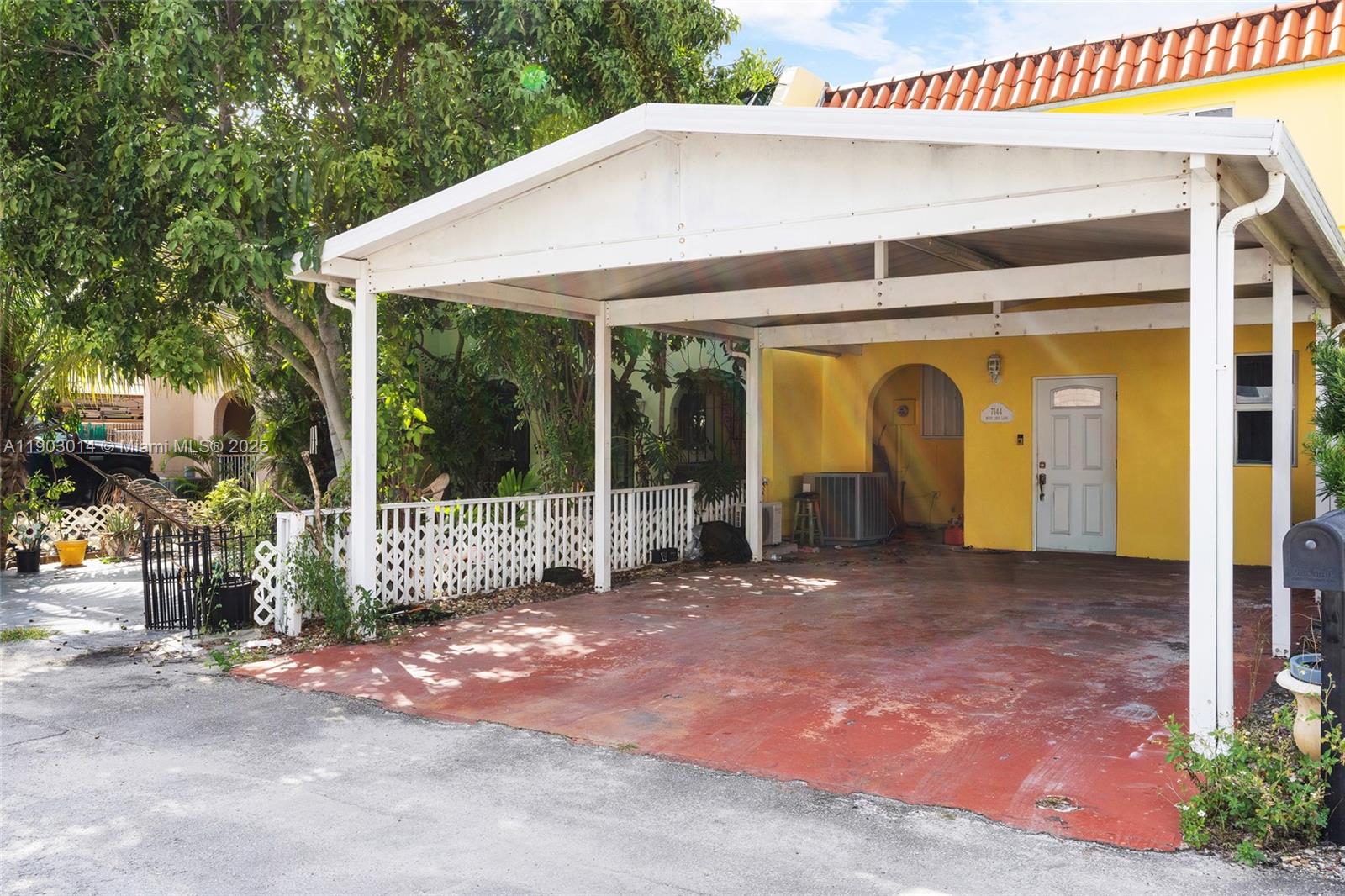 A yellow house features a white carport and a red concrete driveway — 7144 W 2nd Ln, Hialeah FL 33014, HIALEAH, FL