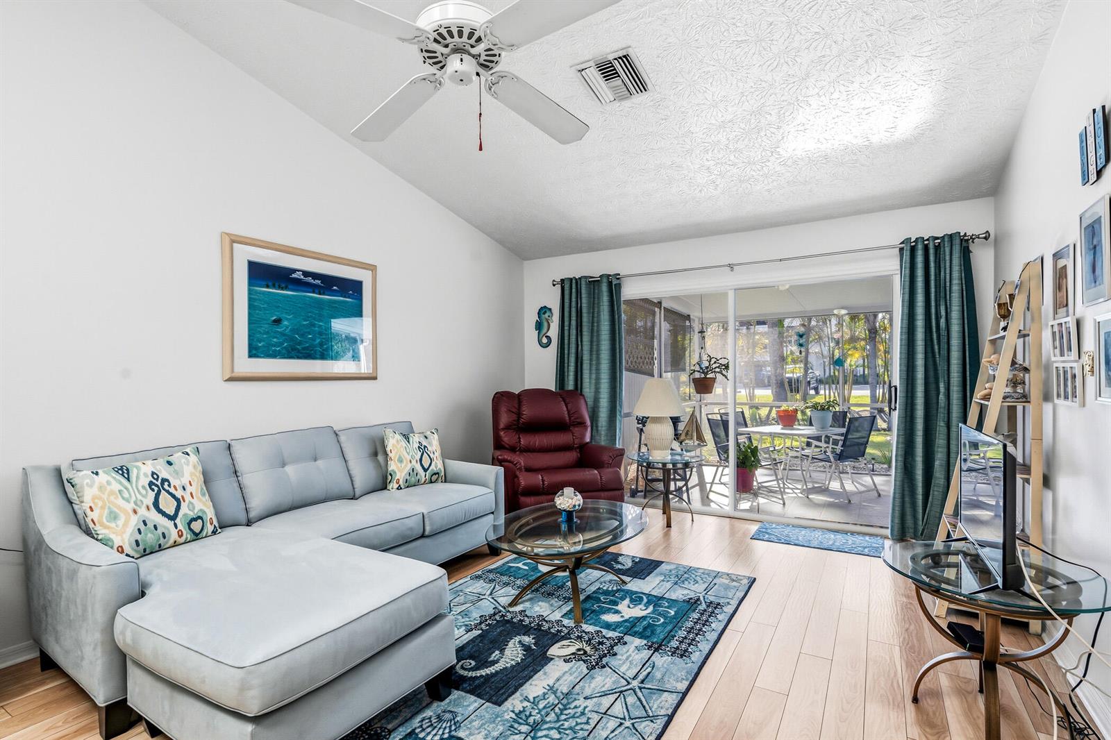 A living room features a light blue sectional sofa, a red recliner, and sliding glass doors — 1866 Sixty Oaks Lane, Vero Beach FL 32966, VERO BEACH, FL