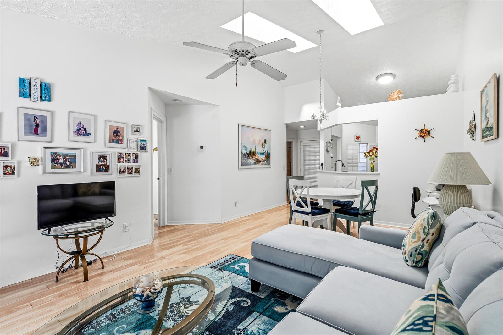 A living room features light wood flooring, a blue sectional sofa, and a ceiling fan — 1866 Sixty Oaks Lane, Vero Beach FL 32966, VERO BEACH, FL