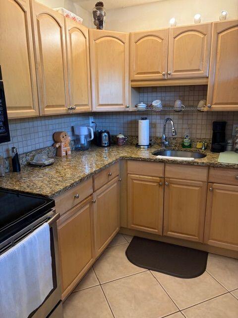 A kitchen features light wood cabinets, granite countertops, and a tiled backsplash — 2562 Garden Drive N # 305, FL 33461, FL
