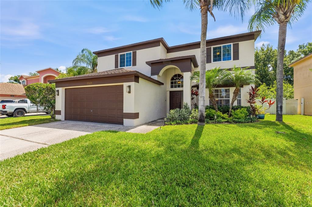 A two-story house with a brown garage, beige stucco exterior, and palm trees in front — 15629 EASTBOURN DRIVE, ODESSA, FL