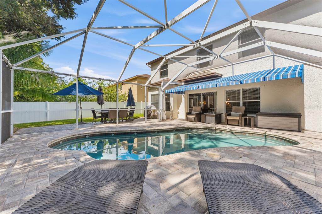 A screened-in patio features a swimming pool, lounge chairs, and a dining area — 15629 EASTBOURN DRIVE, ODESSA, FL