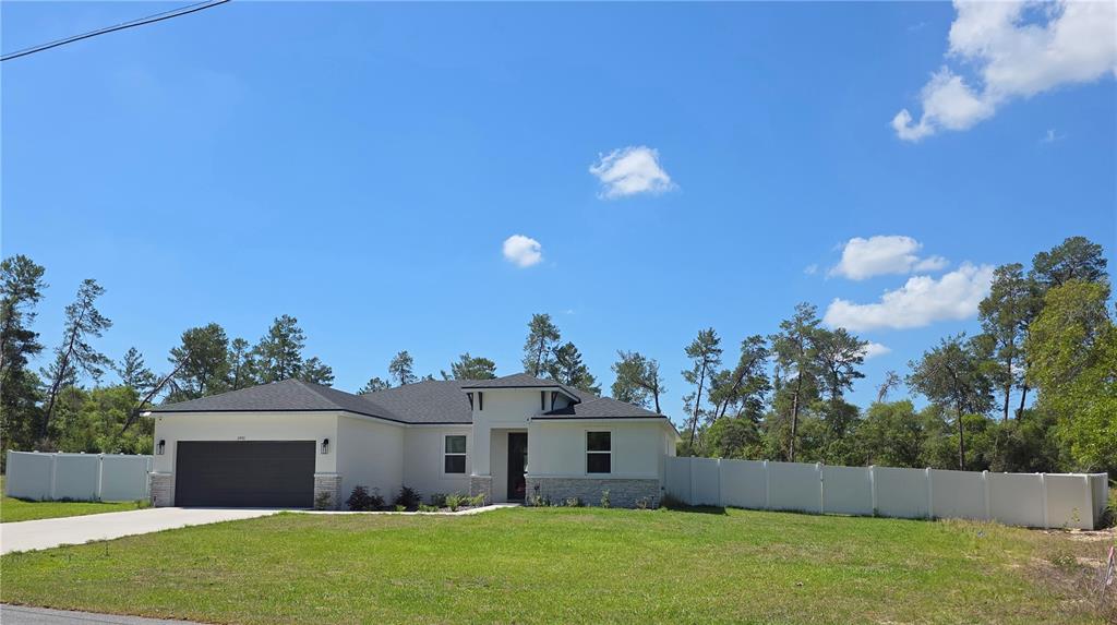 A single-story house with a two-car garage and a white vinyl fence — 2450 SW 170TH LOOP, OCALA, FL