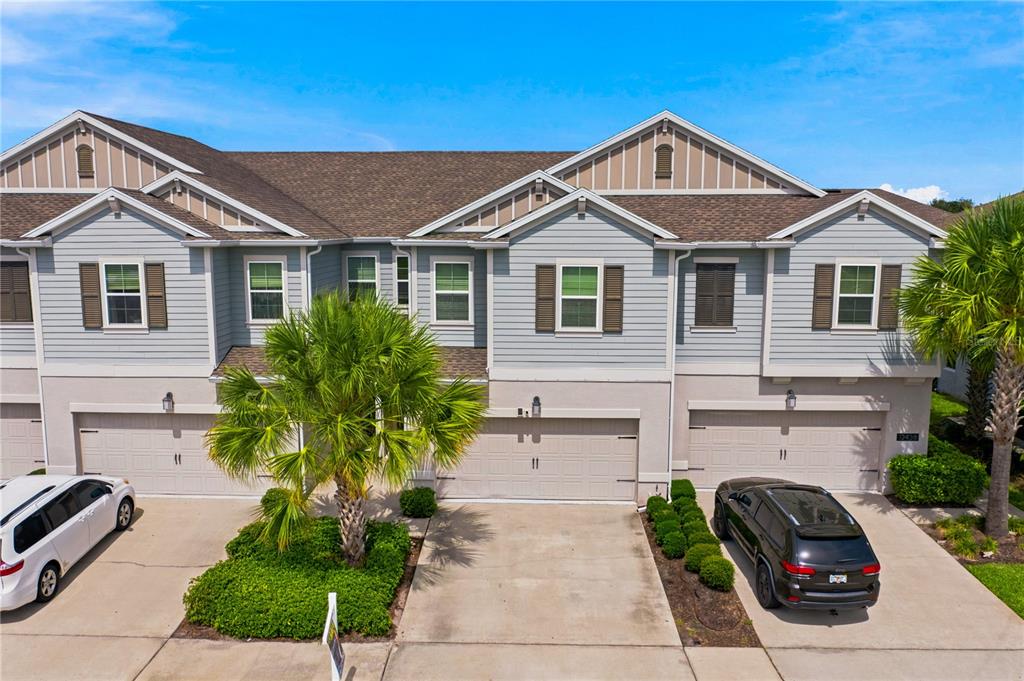 An exterior view of a multi-unit townhouse complex with light blue siding and attached garages — 12444 TURTLE GRASS DRIVE, ORLANDO, FL