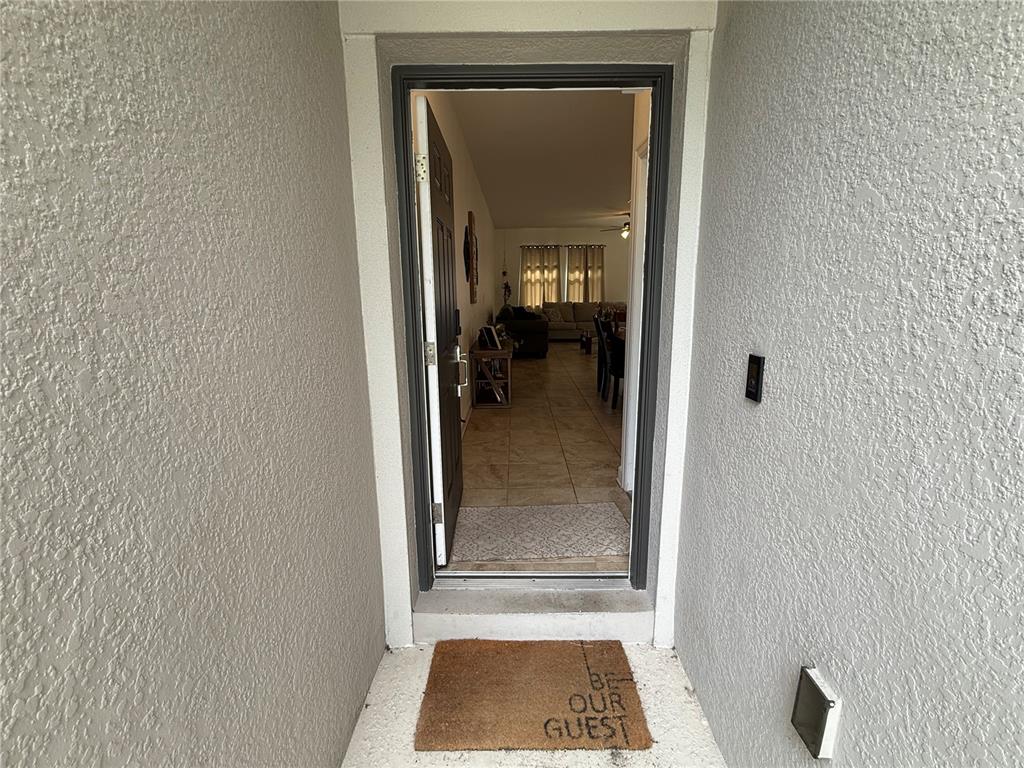 An open front door reveals a tiled entryway leading into a living and dining area — 12444 TURTLE GRASS DRIVE, ORLANDO, FL