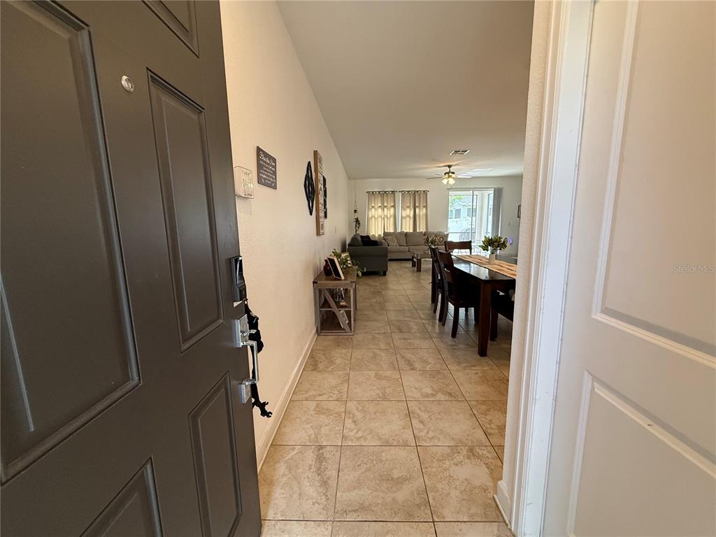 A view from an open front door into a tiled living and dining area — 12444 TURTLE GRASS DRIVE, ORLANDO, FL