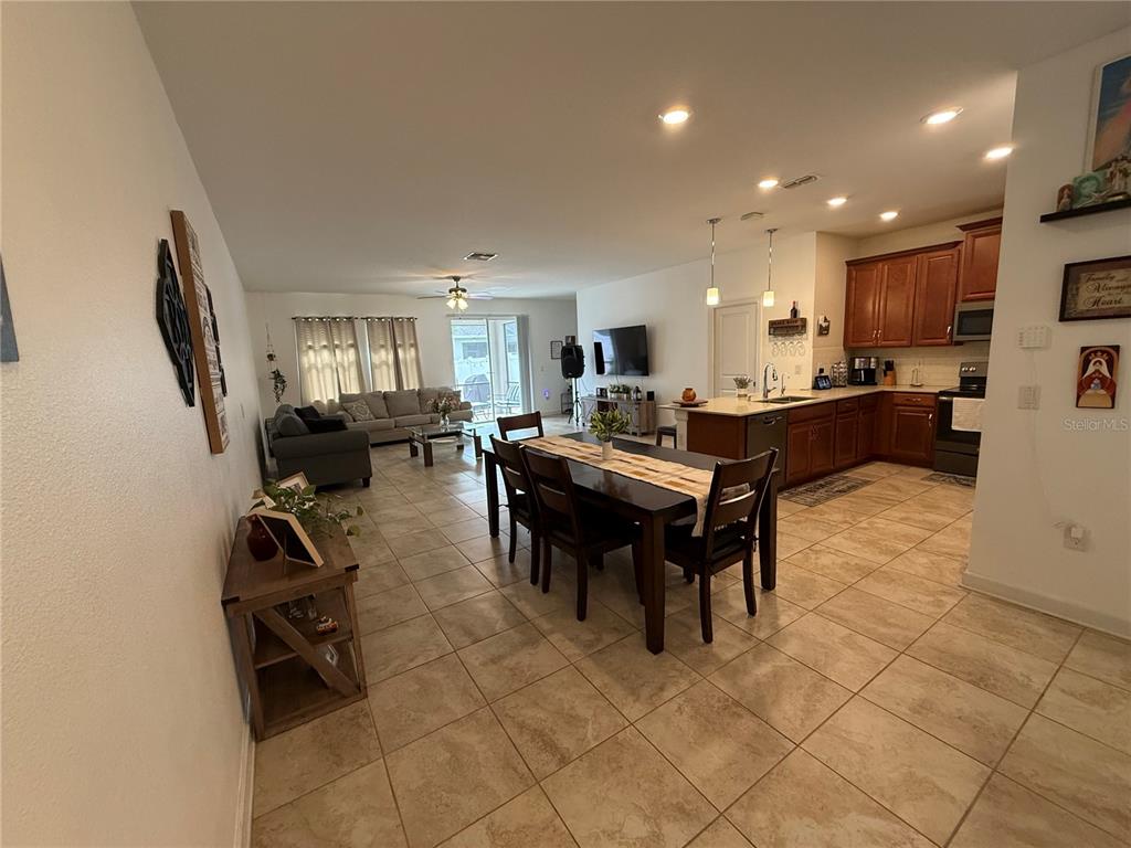 An open-concept living and dining area features tile flooring, wood cabinets, and a kitchen island — 12444 TURTLE GRASS DRIVE, ORLANDO, FL