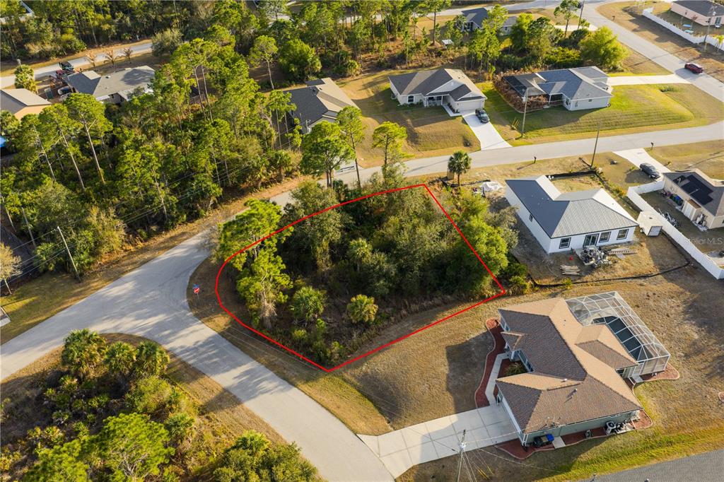 An aerial view shows a vacant, wooded residential lot outlined in red between suburban houses — BECKWITH AVENUE, NORTH PORT, FL