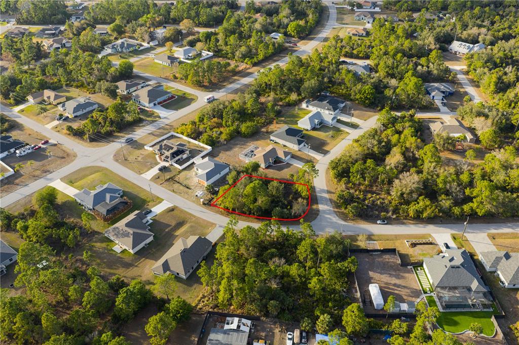 An aerial view shows a vacant, wooded residential lot outlined in red within a neighborhood — BECKWITH AVENUE, NORTH PORT, FL