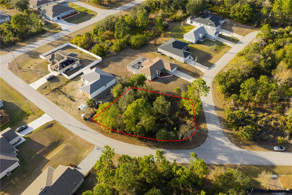 An aerial view shows a vacant, wooded residential lot outlined in red within a neighborhood — BECKWITH AVENUE, NORTH PORT, FL