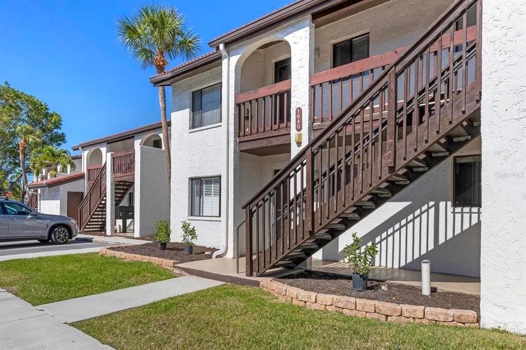 A living room with a sofa and television opens into a bedroom with carpeted floors — 1640 STICKNEY POINT ROAD UNIT 40-101, SARASOTA, FL