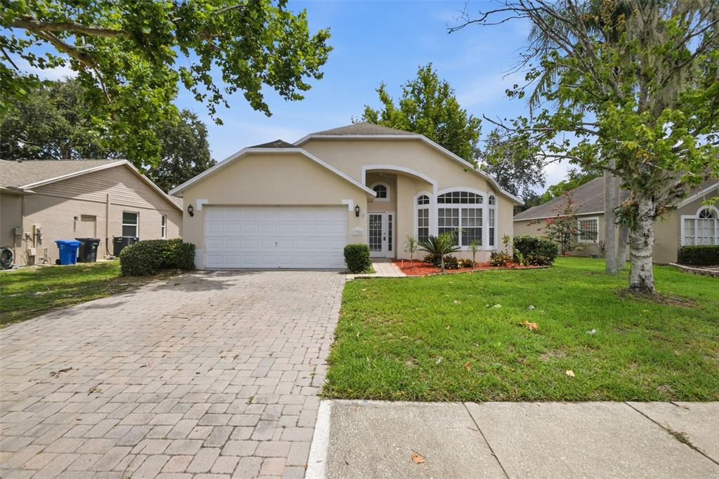 A single-story beige house with a paved driveway, a two-car garage, and a front lawn — 1708 POWDER RIDGE DRIVE, VALRICO, FL