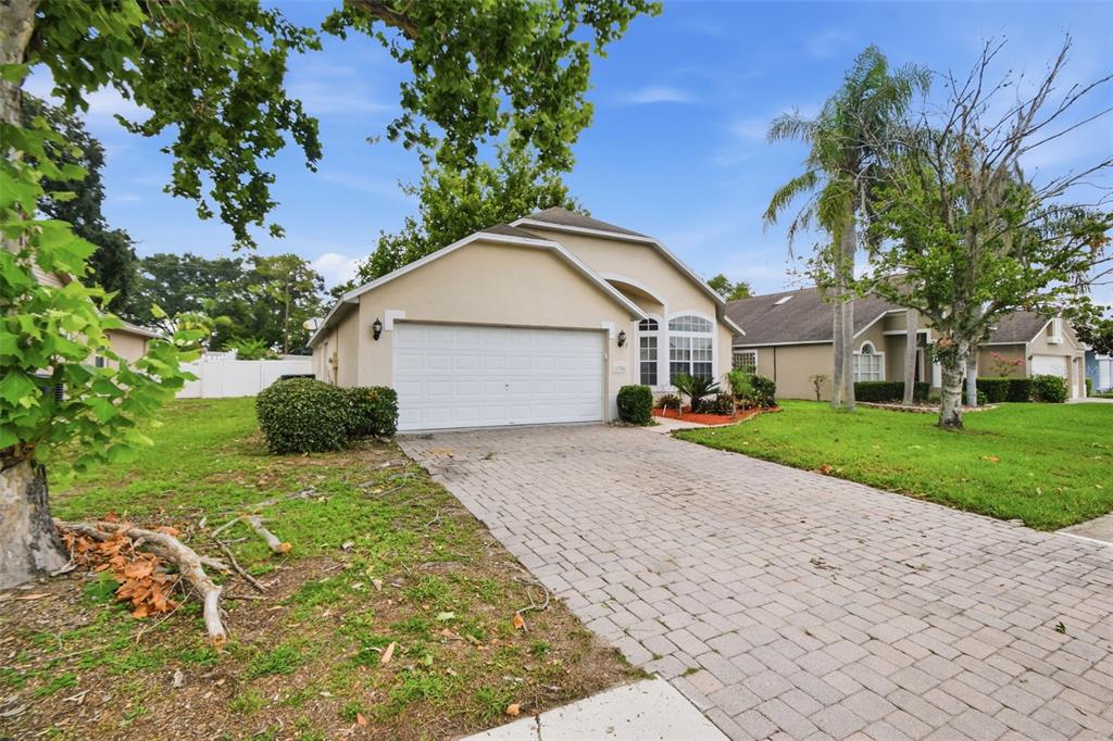 A single-story house with a beige stucco exterior, a white garage door, and a paver driveway — 1708 POWDER RIDGE DRIVE, VALRICO, FL