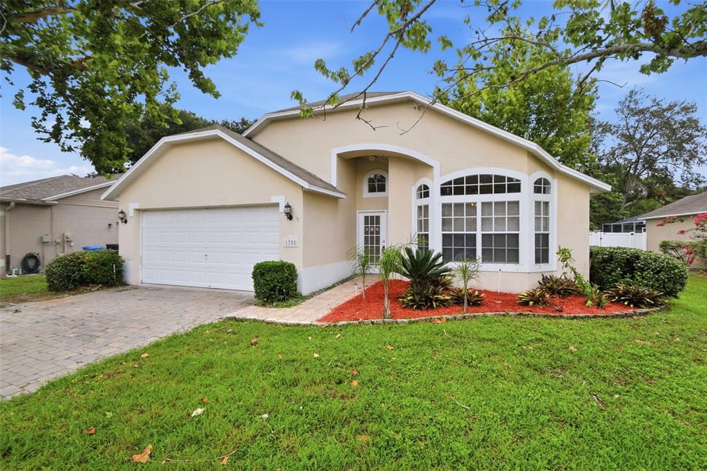 A single-story house with a beige stucco exterior, a two-car garage, and a front garden — 1708 POWDER RIDGE DRIVE, VALRICO, FL