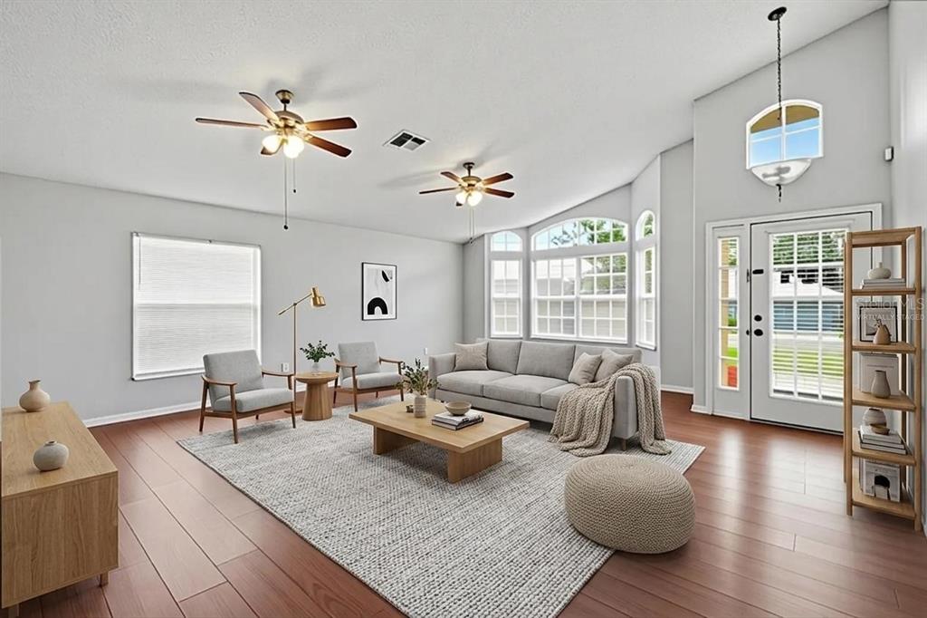 A living room with light gray walls, wood flooring, two ceiling fans, and large windows — 1708 POWDER RIDGE DRIVE, VALRICO, FL