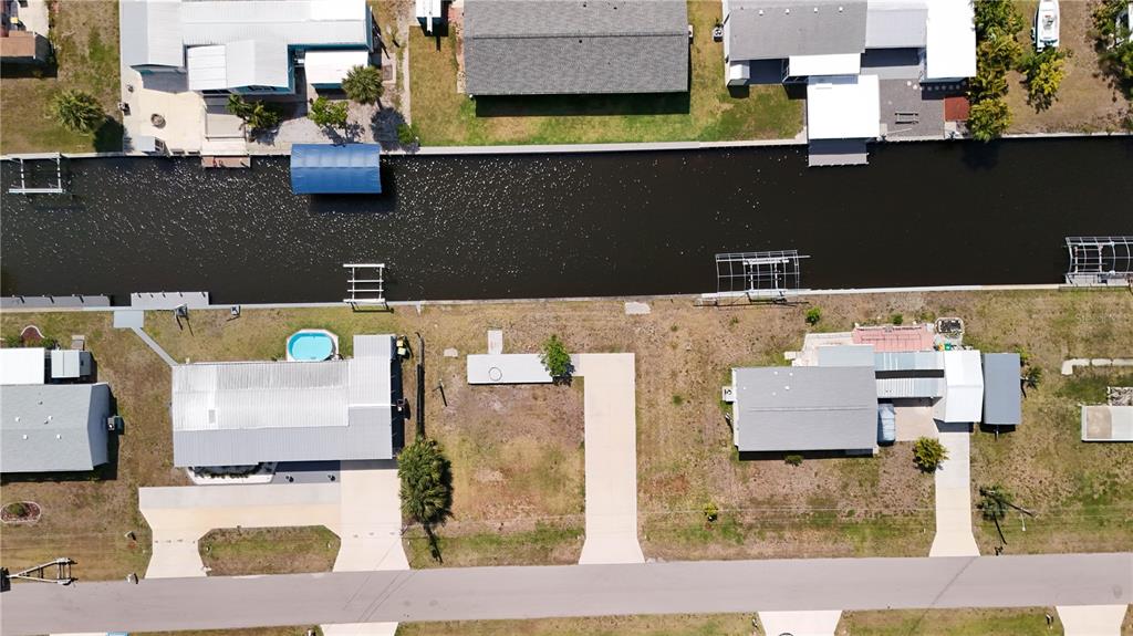 An aerial view shows waterfront homes along a canal with private docks and paved driveways — 4239 WOOD DUCK ROAD, PORT CHARLOTTE, FL