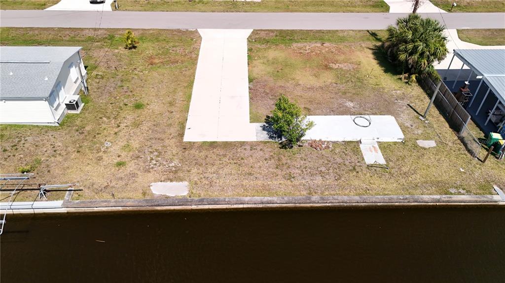 An aerial view shows a vacant waterfront lot with a concrete driveway and small patio — 4239 WOOD DUCK ROAD, PORT CHARLOTTE, FL