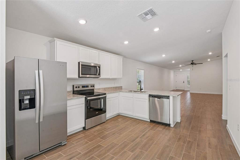 A kitchen with white cabinets, stainless steel appliances, and wood-look tile flooring — 13331 CANADA GOOSE ROAD, WEEKI WACHEE, FL