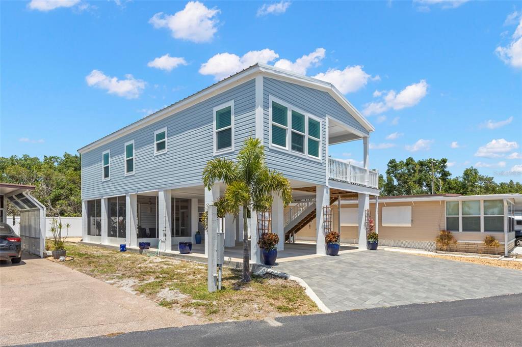 A two-story light blue house on stilts with a paved driveway and a screened patio — 563 MOUNT PINEY AVENUE NE UNIT 691, ST PETERSBURG, FL