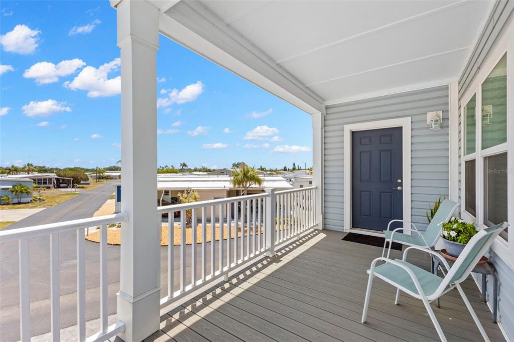 A covered porch with white railings, gray decking, and two chairs overlooks a neighborhood street — 563 MOUNT PINEY AVENUE NE UNIT 691, ST PETERSBURG, FL