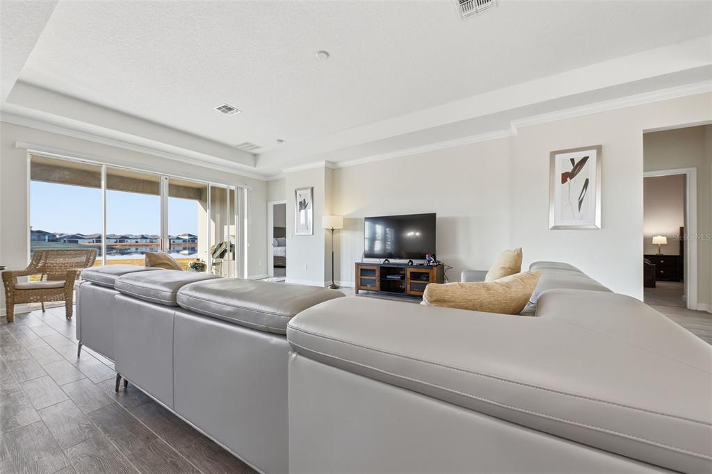 A living room features a large gray sectional sofa, a television, and sliding glass doors — 4524 SEQUEL ROAD, KISSIMMEE, FL
