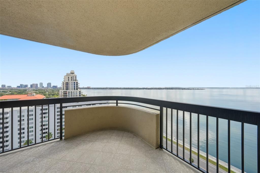 A curved balcony with a black metal railing overlooks a large body of water — 2413 BAYSHORE BOULEVARD UNIT 2001, TAMPA, FL