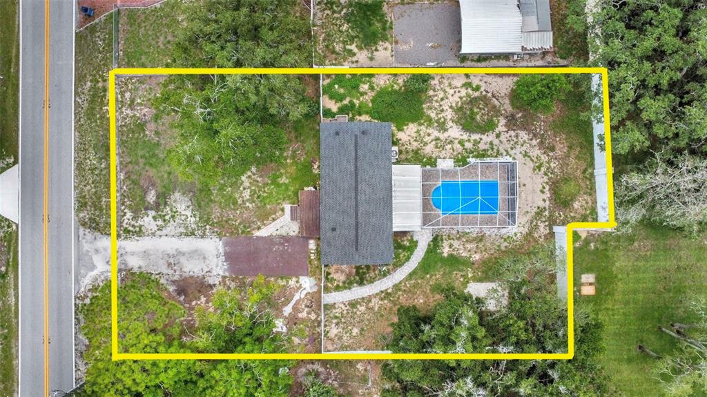 An aerial view shows a house with a screened pool on a large, wooded lot — 7194 SEALAWN DRIVE, SPRING HILL, FL