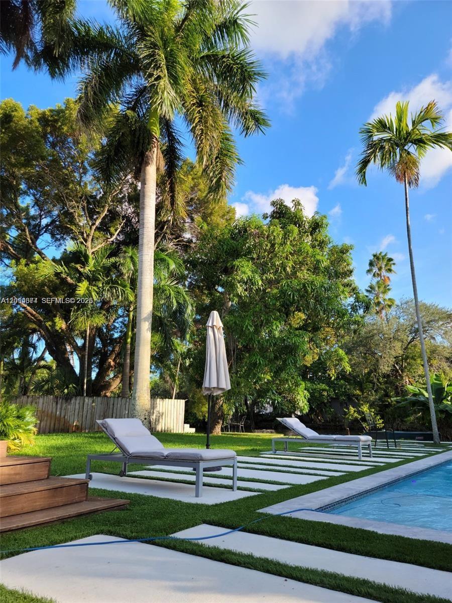 A backyard features a swimming pool, lounge chairs, and palm trees on a sunny day — 336 NE 85, El Portal FL 33138, EL PORTAL, FL