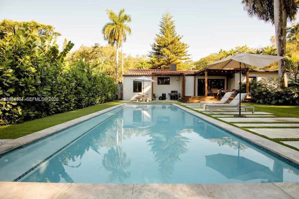 A rectangular swimming pool sits in a backyard with a house, patio, and palm trees — 336 NE 85, El Portal FL 33138, EL PORTAL, FL