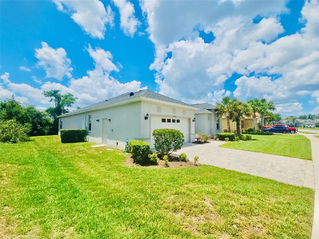 A single-story house with a white exterior, a paved driveway, and a green lawn — 19736 LONESOME PINE DRIVE, LAND O LAKES, FL