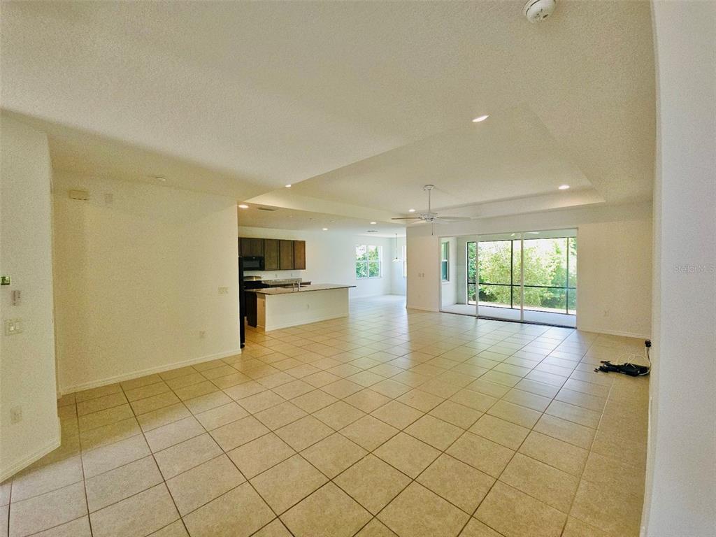 An open-concept living area features tile flooring, a kitchen with an island, and sliding doors — 19736 LONESOME PINE DRIVE, LAND O LAKES, FL