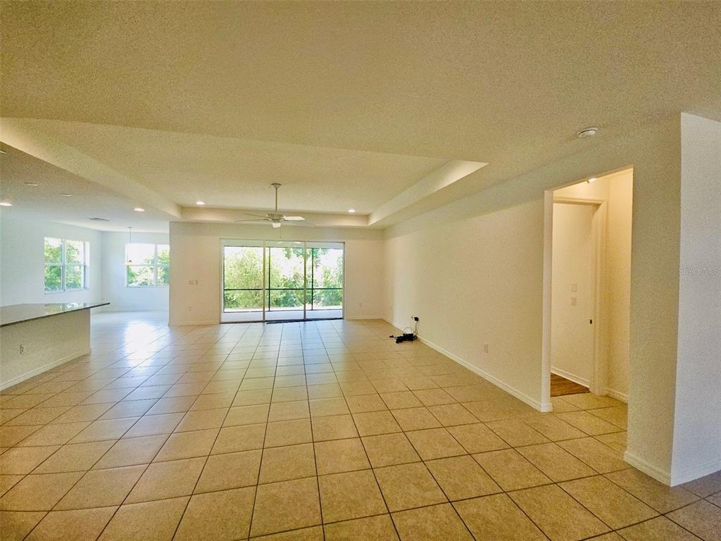 An open-concept living area with tile flooring, a tray ceiling, and sliding glass doors — 19736 LONESOME PINE DRIVE, LAND O LAKES, FL