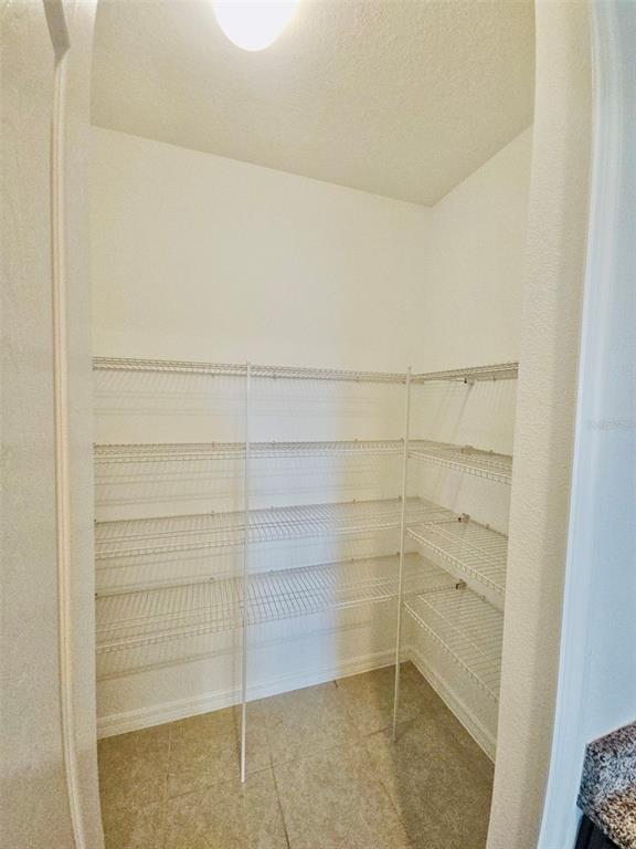 A walk-in pantry features white walls, tile flooring, and multiple levels of white wire shelving — 19736 LONESOME PINE DRIVE, LAND O LAKES, FL