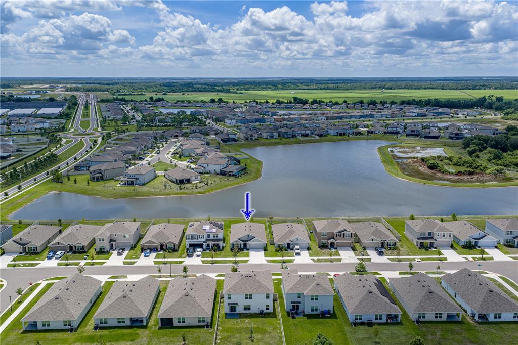 An aerial view shows a suburban neighborhood with a blue arrow pointing to a house — 3062 LIVING CORAL STREET, WIMAUMA, FL
