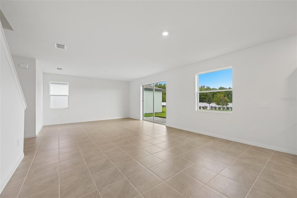 An empty living room features light-colored tile flooring, white walls, and a sliding glass door — 4508 OUTHAUL RUN, PALMETTO, FL